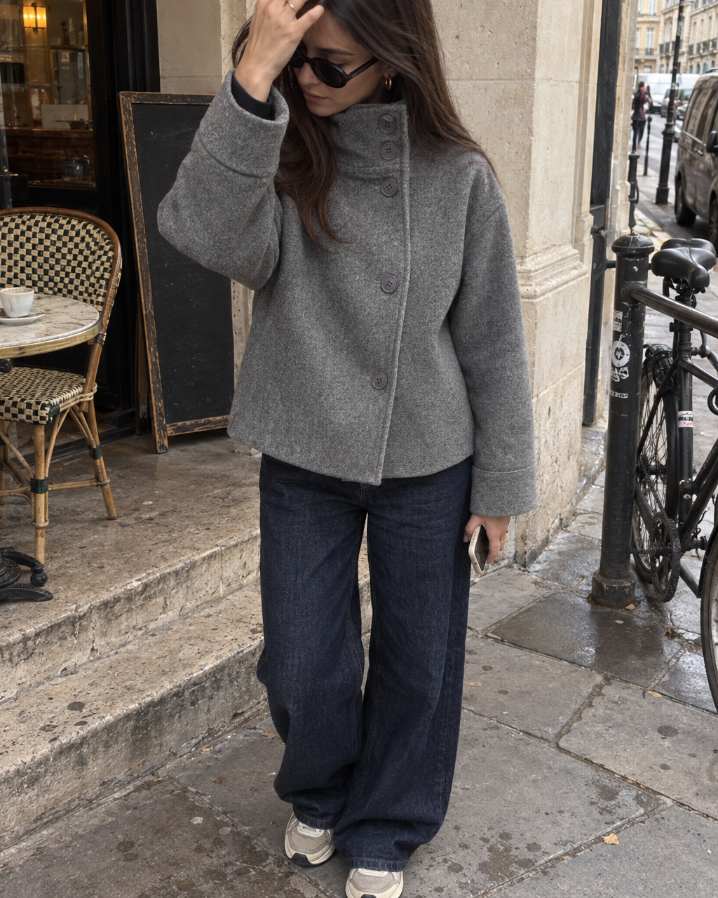 The Copenhagen Coat in Storm, worn with wide-leg jeans and sneakers outside a cafe